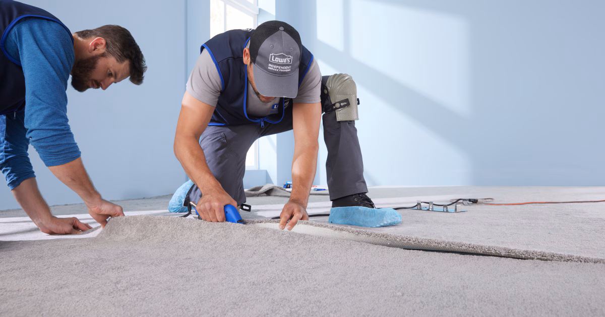 Workers installing carpet in a room.