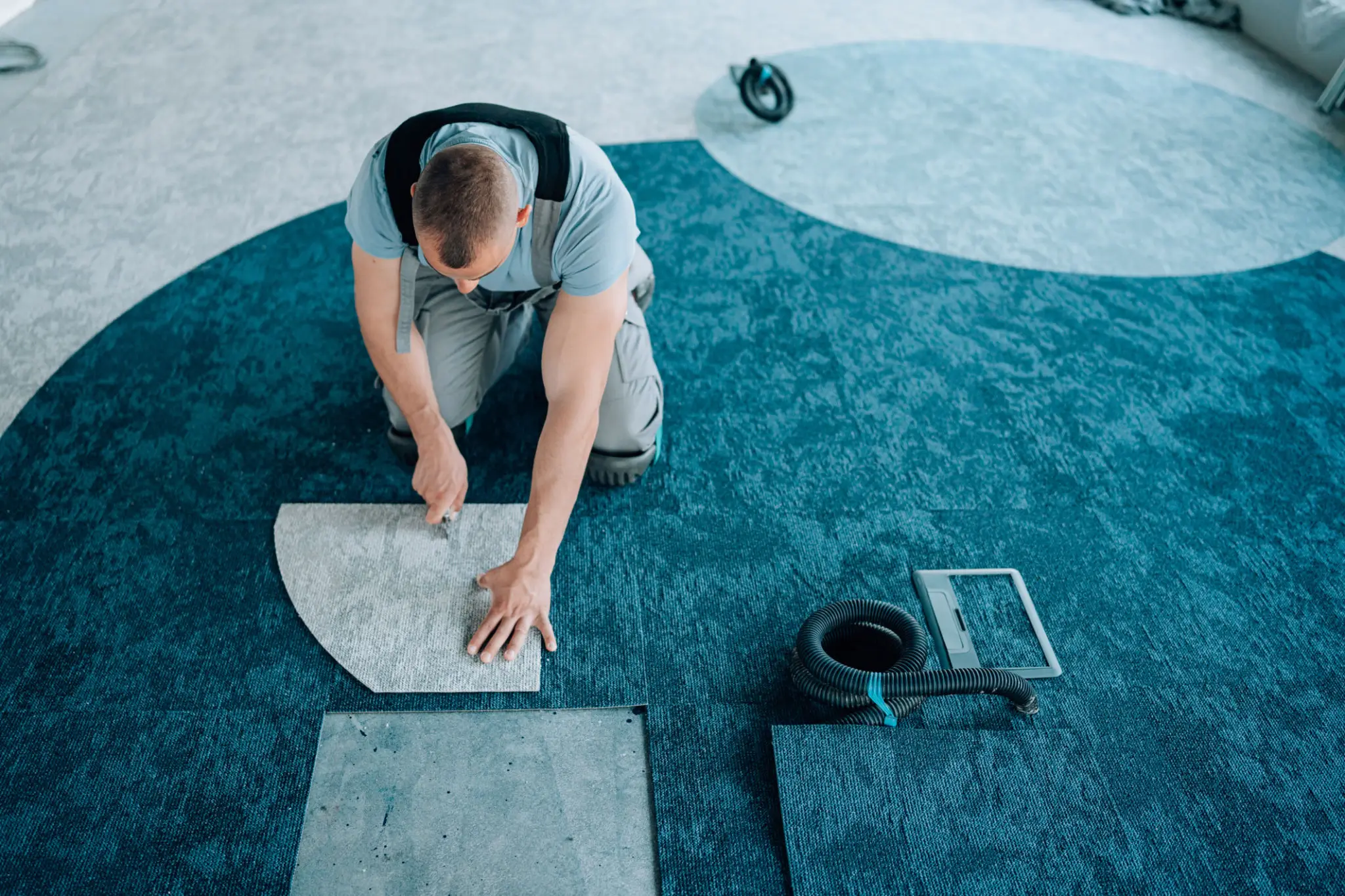 Man installing carpet tiles on floor.