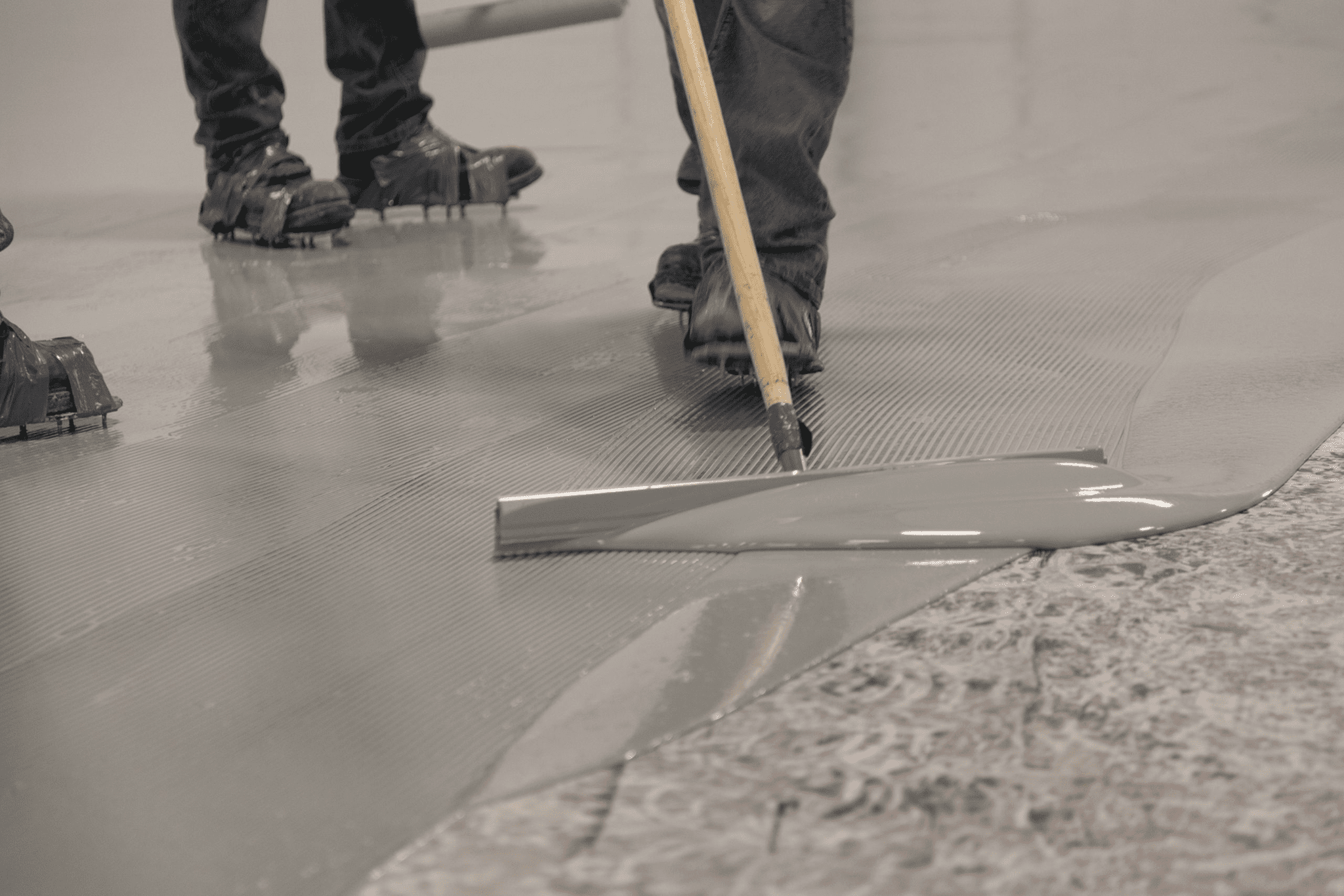 Applying epoxy flooring with squeegee tool.