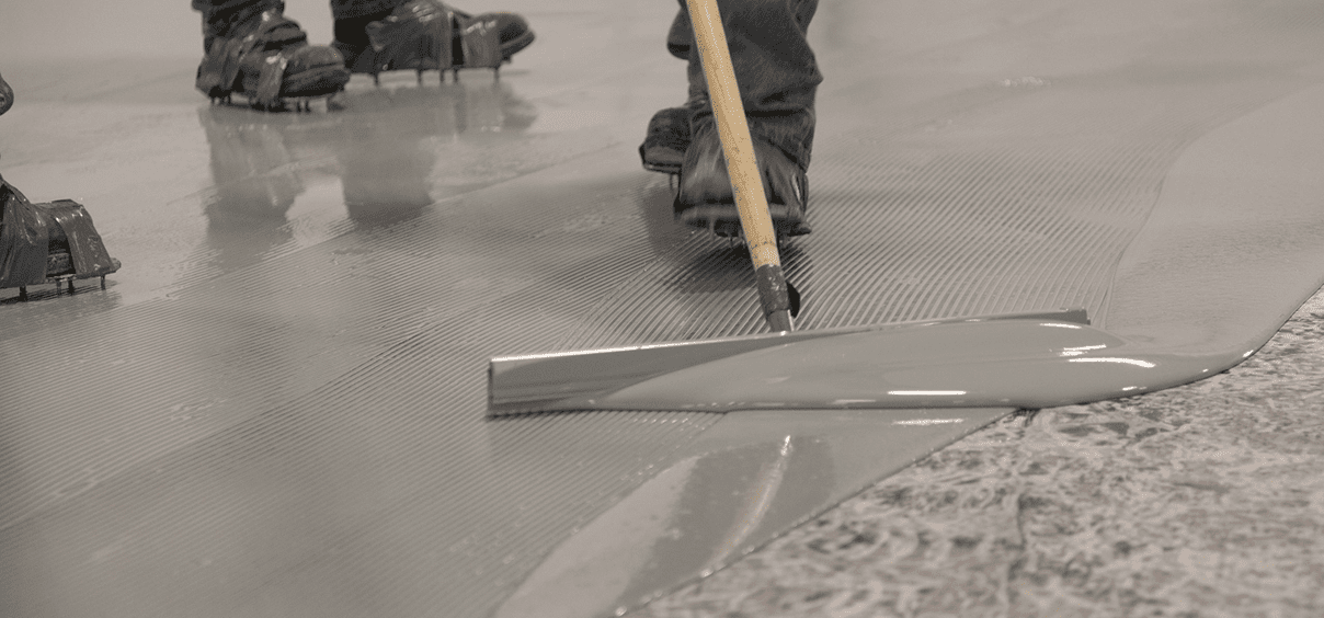 Smoothing wet concrete with a long tool.