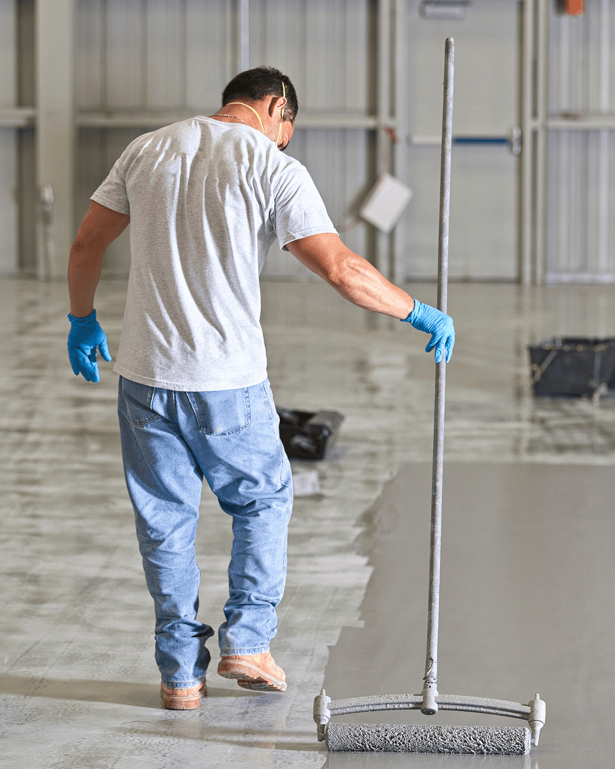 Man painting floor with roller indoors.